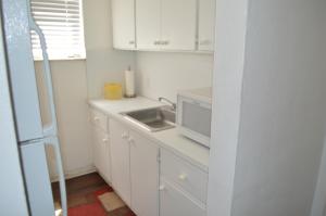 a white kitchen with a sink and a microwave at Island House South Beach in Miami Beach