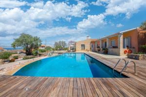 uma piscina com um deque de madeira e uma casa em Estate Prophet Elias em Egina