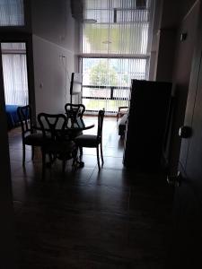 Habitación oscura con mesa, sillas y ventana en Casa Bertha Hotel y Servicios SAS, en Nobsa