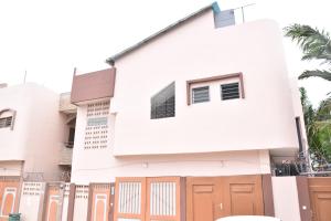 uma casa branca com portas laranja e uma cerca em Tranquillité Cotonou em Cotonou