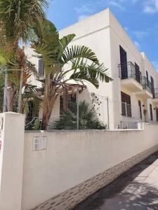 a white building with palm trees next to a wall at B&B Agrodolce in San Vito lo Capo