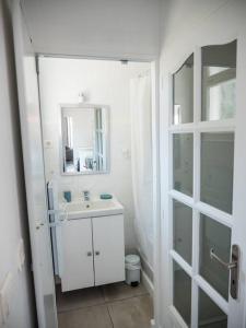 a white bathroom with a sink and a mirror at Logement Le Serein in Toulon