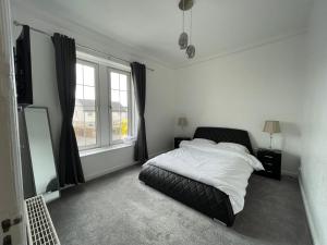 a bedroom with a bed and a large window at Premier Apartment C in Broxburn