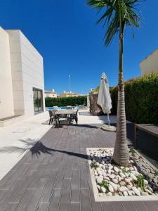 eine Palme auf einer Terrasse mit einem Tisch und Stühlen in der Unterkunft Luxury city Villa Olivia 10 - 15 min to the Beach Oura, private swimming pool in Albufeira