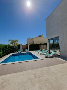 einen Pool mit Liegestühlen neben einem Gebäude in der Unterkunft Luxury city Villa Olivia 10 - 15 min to the Beach Oura, private swimming pool in Albufeira