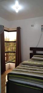a bedroom with a bed and a large window at Leonor's Transient House in Polangui