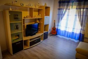 uma sala de estar com um centro de entretenimento com uma televisão e uma guitarra em Appartamento con tre camere - Zona Centrale em Alessandria