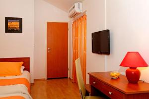 a bedroom with a bed and a desk and a tv at Guest House Kod Peskarije in Vela Luka