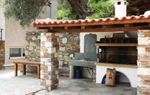 a patio with a stone oven and a bench at Naiades Villas in Karistos