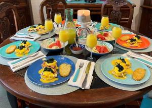 a wooden table with plates of food and orange juice at The Mermaid and The Pearl Boutique B&B in Isla Mujeres