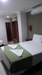 a bedroom with a bed with a green blanket and white pillows at Pousada Nova Oasis do Rei in Canoa Quebrada