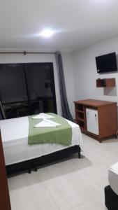 a bedroom with a bed and a dresser and a television at Pousada Nova Oasis do Rei in Canoa Quebrada