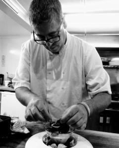 un hombre en una cocina preparando comida en un tazón en Orchard Lodge & Wolds Restaurant en Scarborough