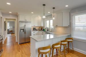 a kitchen with white cabinets and a island with bar stools at Chic Home with Deck, Walk to Lake Erie! 