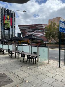 um grupo de mesas e cadeiras com guarda-sóis num passeio em 2br ANTEA Embassy free parking em Adelaide