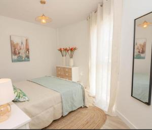 ein weißes Schlafzimmer mit einem Bett und einem Fenster in der Unterkunft Apartamento Jacaranda in La Herradura