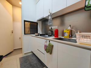 a kitchen with white cabinets and a sink at Midvalley Luxury Maxine Suite in Kuala Lumpur