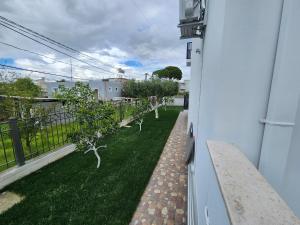 Vila Anxhelo&Xhemi في فلوره: صف من الأشجار على عشب بجوار منزل