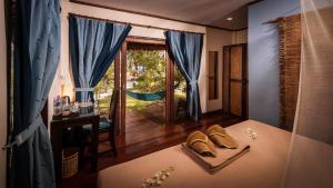 a bedroom with a bed with blue curtains and a window at Baan Manali Resort in Thongsala