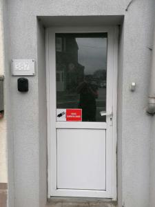 a person standing behind a door with a sign in it at La Maison Heureuse in Châtelet