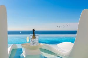 uma garrafa de vinho sentada numa taça numa mesa perto do oceano em Blue Sky Mallorca Luxury Villa em Andraitx