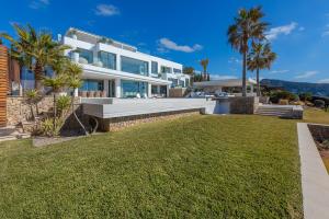 duży dom z trawnikiem przed nim w obiekcie Blue Sky Mallorca Luxury Villa w mieście Andratx