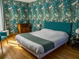 a bedroom with a bed with a green headboard and wallpaper at Maison du Moulin in Donzy