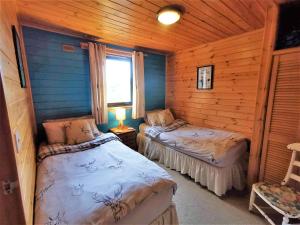 een slaapkamer met 2 bedden in een blokhut bij Glen Bay - 2 Bed Lodge on Friendly Farm Stay with Private Hot Tub in New Cumnock