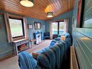una sala de estar con sofás azules en una sala de tren en Glen Bay - 2 Bed Lodge on Friendly Farm Stay with Private Hot Tub en New Cumnock