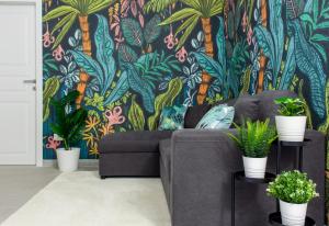 ein Wohnzimmer mit einem Sofa und einer tropischen Tapete in der Unterkunft Tropical - Boutique Apartment in Gallipoli