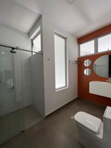 La salle de bains est pourvue de toilettes et d'une douche en verre. dans l'établissement Hotel Emerawaa Centro Historico, à Ríohacha