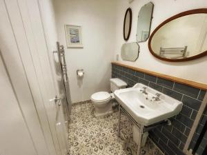 a bathroom with a sink and a toilet and a mirror at Millpool House in Dartmouth