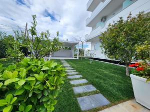 un jardin avec des plantes vertes et une passerelle dans l'établissement Vila Anxhelo&Xhemi, à Vlorë