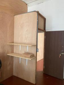 a room with a wooden wall with shelves and a door at Puente Real Hostel in Liberia