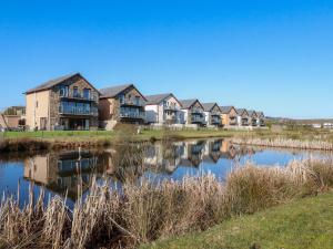 a row of houses next to a pond at 207 The Glades - Retallack Resort and Spa in Saint Columb Major