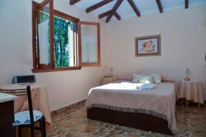a bedroom with a bed and two tables and a window at Castelar - Hotel & Apart in Huerta Grande