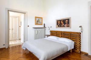 a bedroom with a large white bed with a wooden headboard at Italy Prestigious Guest House in Bologna