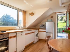 une cuisine avec des placards blancs, une table et une fenêtre dans l'établissement Goody, à Kingsbridge