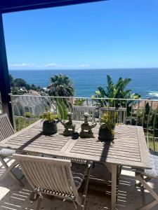 a wooden table with potted plants on a balcony at Villa del Mar - "Luxurious en-suite bedroom with lounge and stunning sea view balcony in Bantry Bay" in Cape Town