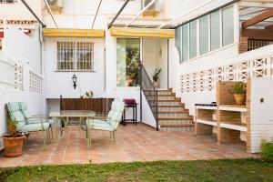 een patio met een tafel en stoelen naast een huis bij Casa Jardín - residential area -free parking outdoor- Málaga Este in Málaga