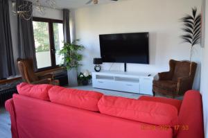 a living room with a red couch and a flat screen tv at Dolomitenblick in Gerolstein