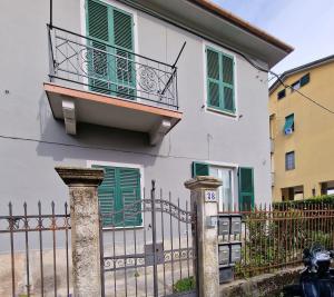 a white house with green shutters and a fence at FLORA HOUSE in La Spezia