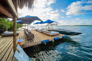 a dock with chairs and umbrellas and a boat on the water at Hotel Agua Baru by Mustique in Baru