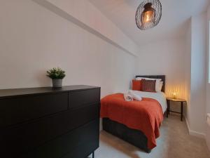 a bedroom with a bed with a red blanket and a dresser at South Terrace Apartment by Cliftonvalley Apartments in Weston-super-Mare