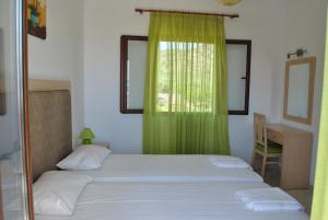 a bedroom with a bed with a green curtain and a desk at Antigoni Apartments 'Olive Room' in Milatos