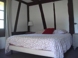een slaapkamer met een bed met een rood kussen erop bij Propriété à 5 km de Honfleur in Fourneville
