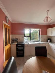 a kitchen with red walls and a table and a stove at Heather Hill Cottage in Downings