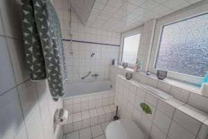 a bathroom with a toilet and a tub and a window at KobyApartment in Herford