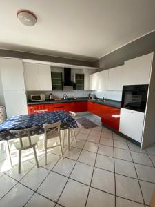 una cucina con armadi rossi e bianchi, tavolo e sedie di Spazio Friuli - Soreli Apt residenza nel verde a Sevegliano