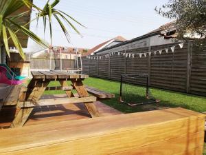 een houten picknicktafel op een terras met een schommel bij La maison du Lhéris in Bagnères-de-Bigorre